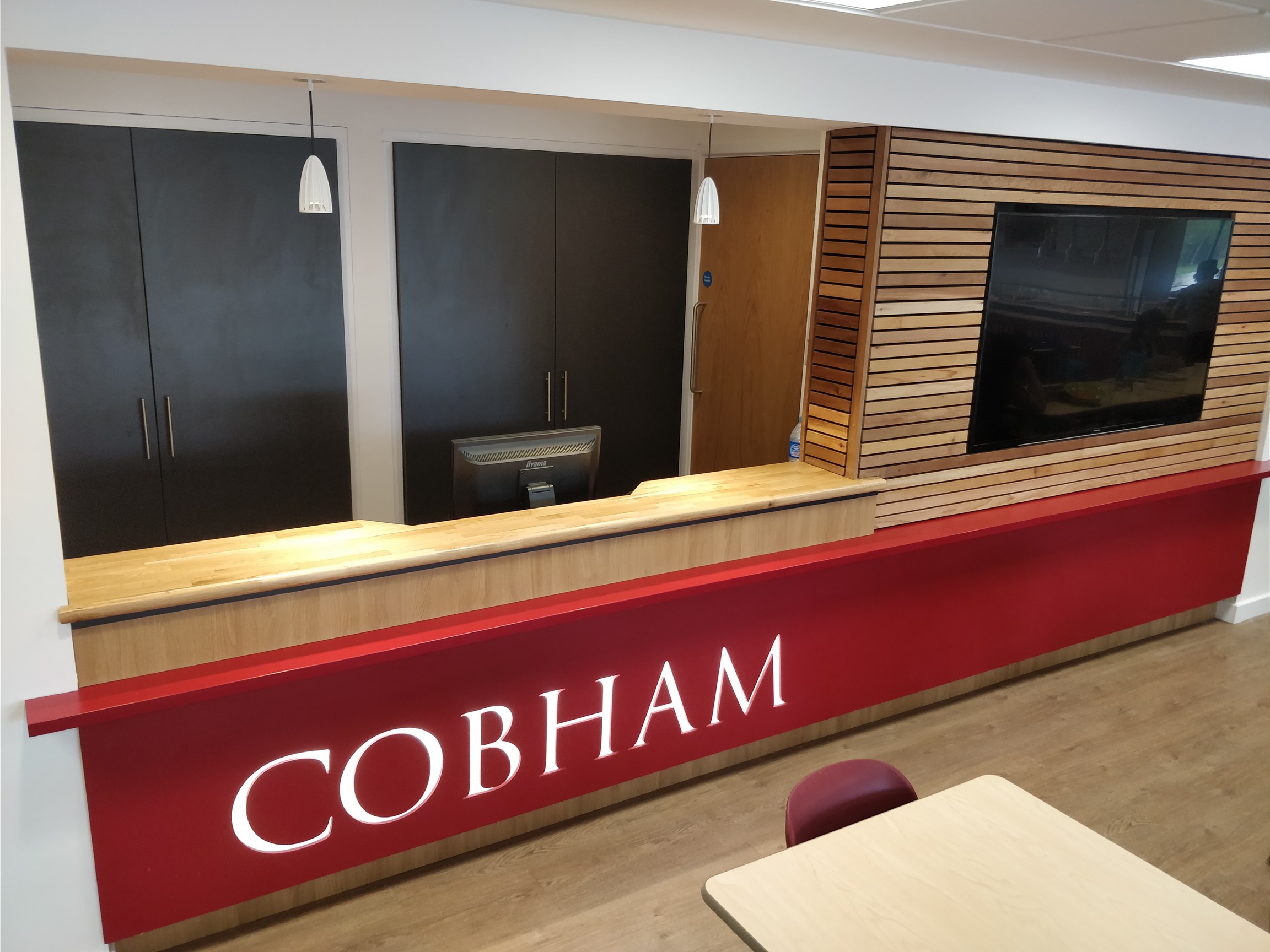 Bespoke Cobham reception counter with red branded front and timber slatted screen