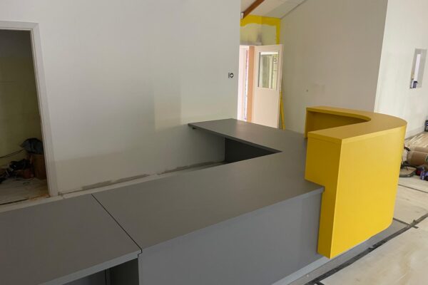 Curved yellow reception shroud and grey worktops at Dogs Trust Kenilworth