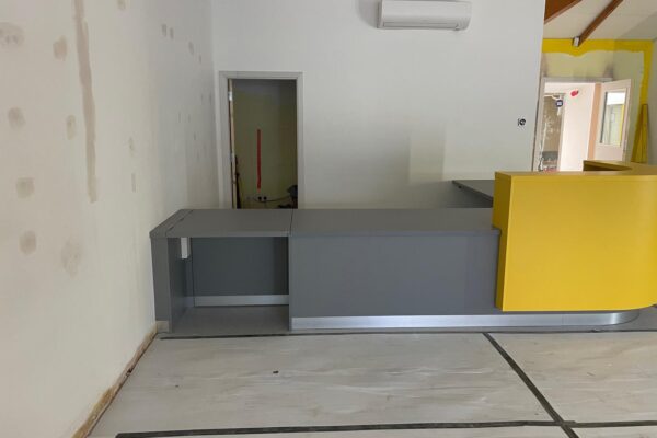 Accessible grey counter with hinged flap beside the yellow reception desk at Dogs Trust Kenilworth